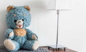 Välityksessä olleen asunnon pöytä, jossa sininen nalle-pehmolelu ja valkoinen pöytälamppu